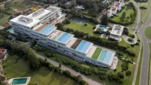 Acqua em primeiro plano: os terraços em cascata exibem piscinas infinitas privativas que se fundem com o horizonte do Atlântico, diluindo os limites entre arquitetura e paisagem.